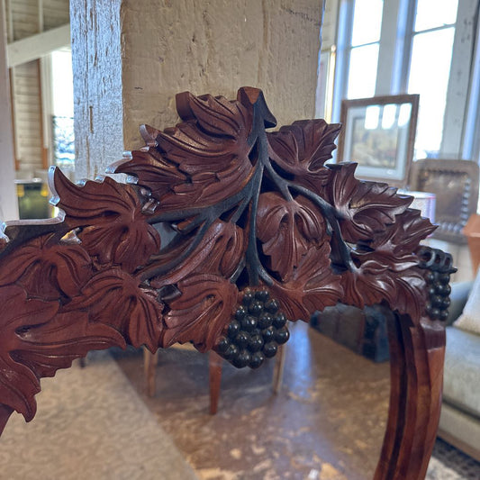 Carved wooden chair with intricate leaf patterns in a room setting