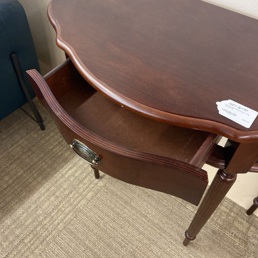 Wooden side table with a drawer on a carpeted floor
