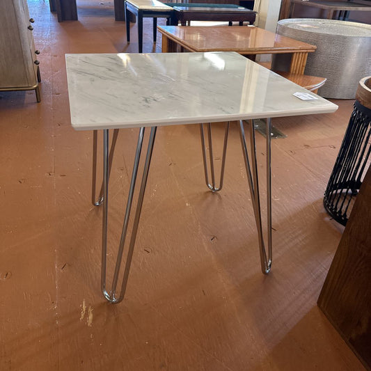 Table with marble-like top and metal legs on a wooden floor