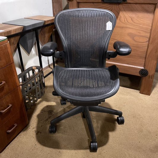 Black office chair in a room with wooden furniture and a carpeted floor.