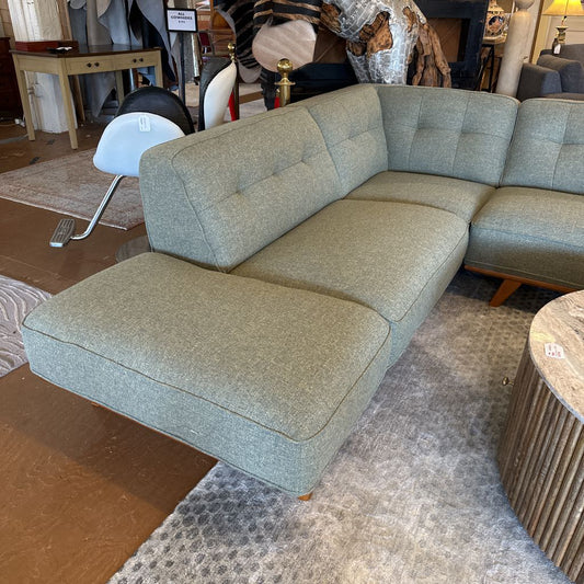 Gray sectional sofa in a showroom setting with other furniture items.