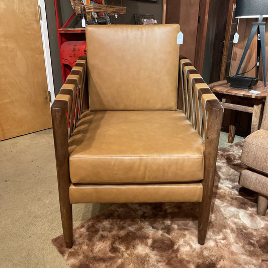 Brown leather armchair in a store setting with other furniture items.