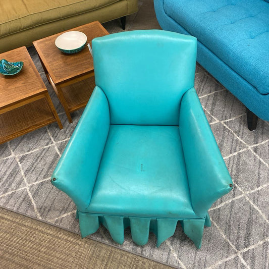 Turquoise chair in a living room setting with wooden tables and a blue couch.