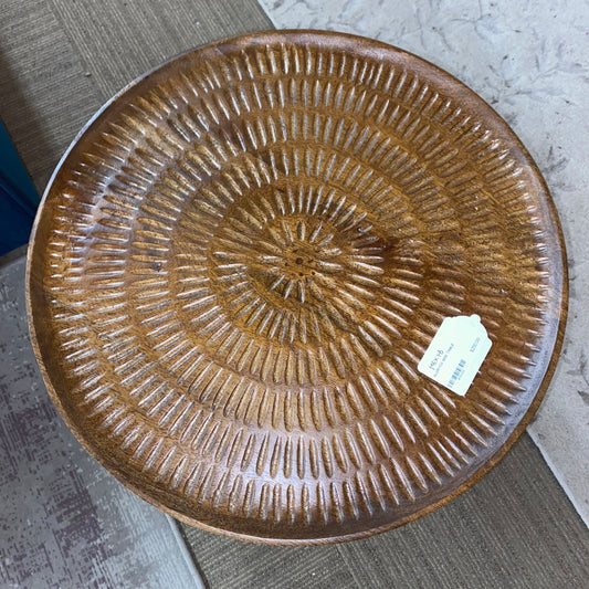 Wooden side table with textured surface on a carpeted floor