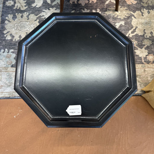 Black octagonal tray on a wooden surface with a patterned rug in the background