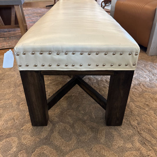 Beige upholstered bench with wooden legs on a carpeted floor