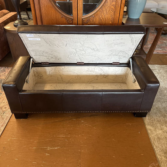 Brown leather ottoman with open lid revealing a marble-like interior.
