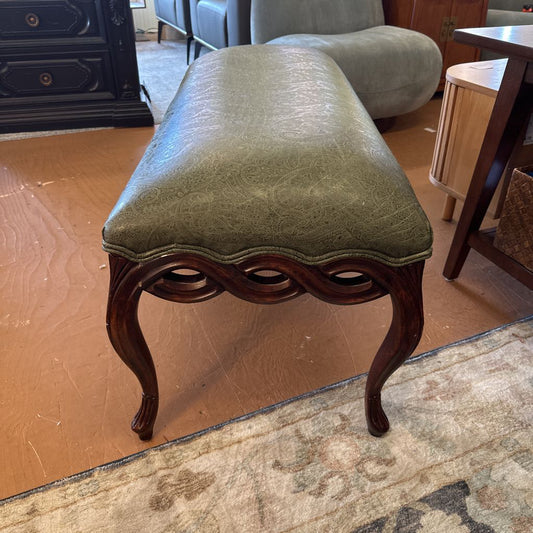 Green upholstered bench with wooden legs in a room setting