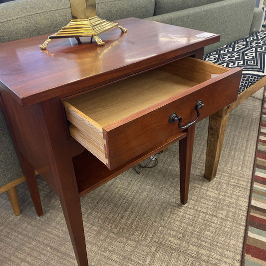 Wooden side table with an open drawer in a room setting