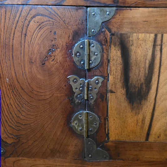 Close-up of a wooden cabinet with metal hinges