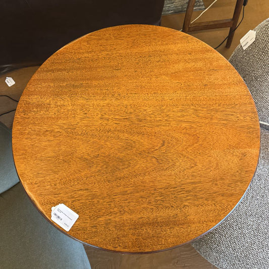Round wooden table with a visible price tag on a floor setting