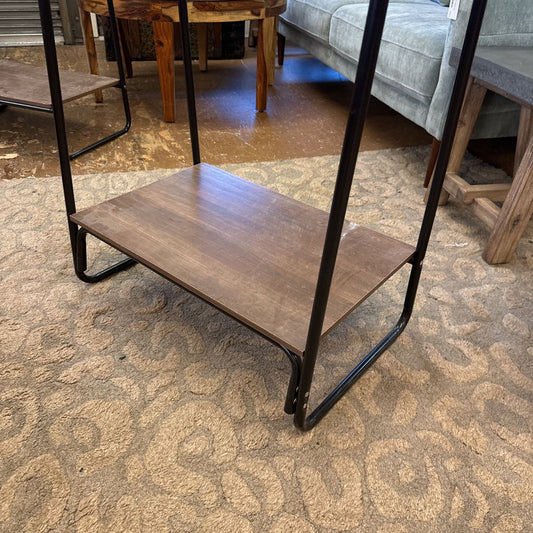 Wooden shelf with black metal legs on a patterned carpet
