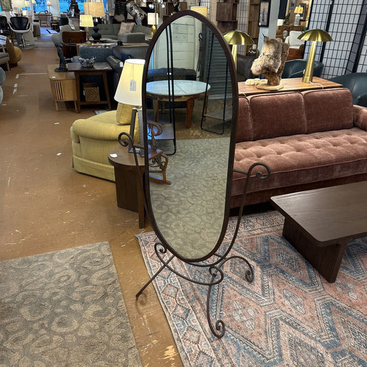 Oval freestanding mirror in a room with furniture and decor