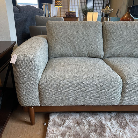 Gray textured sofa with wooden legs in a room setting