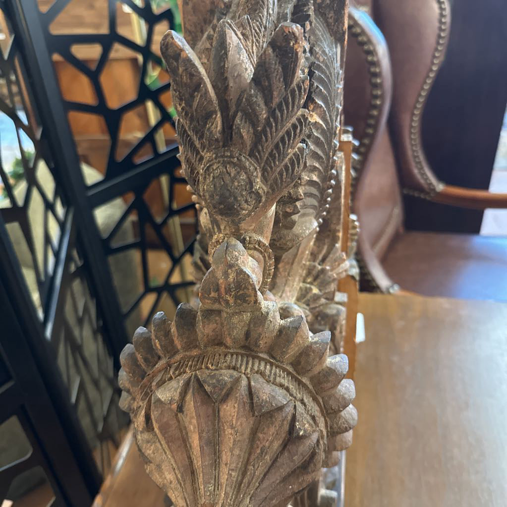 Decorative wooden finial with intricate carvings in a room setting