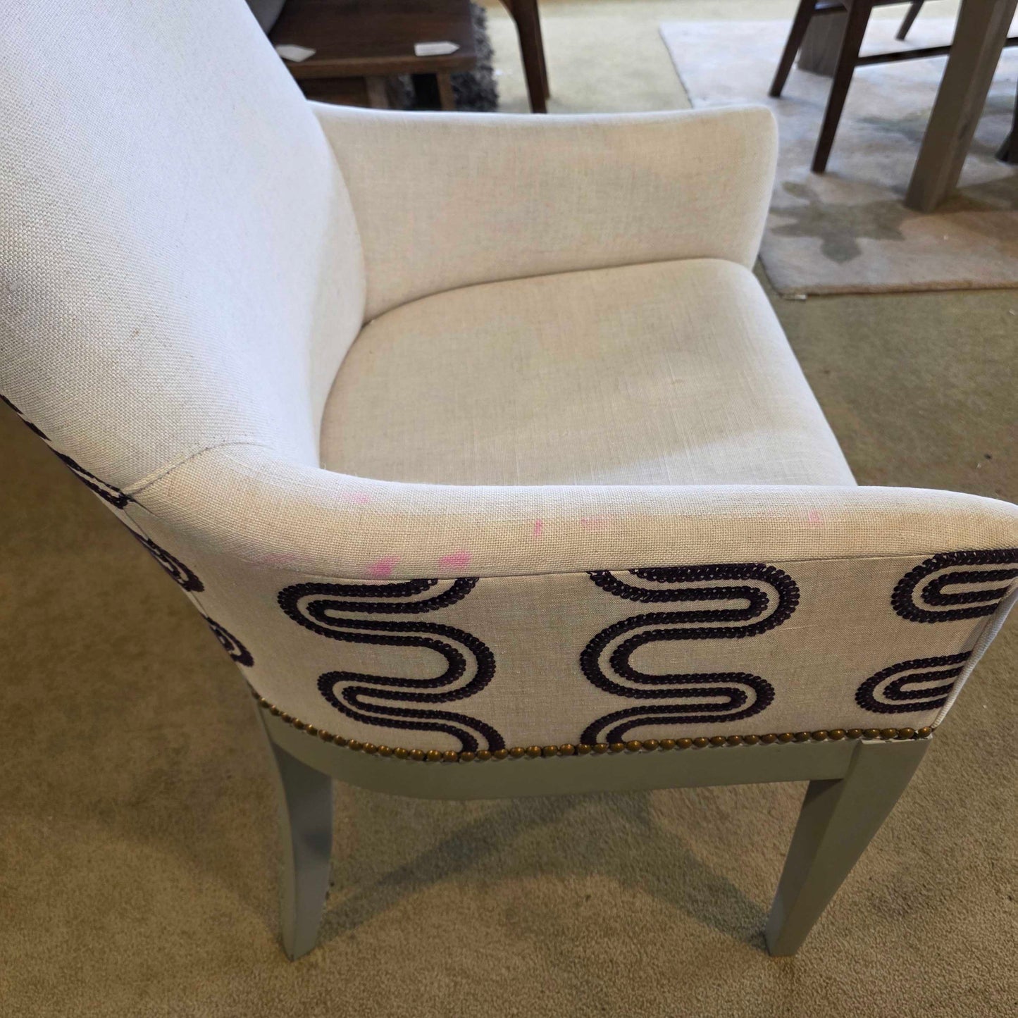 Beige armchair with a decorative pillow featuring black wavy patterns.