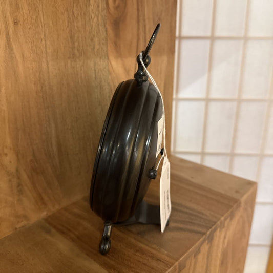 Black metal reel on a wooden shelf with a tag