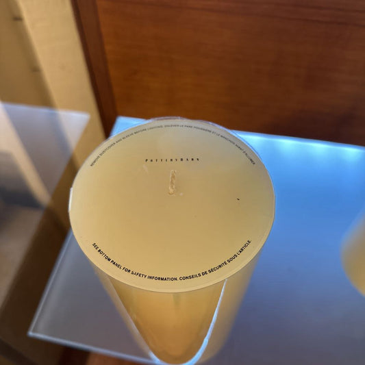 White candle with text on a reflective surface