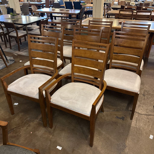 Wooden chairs with white cushioned seats in a room with tables and chairs.