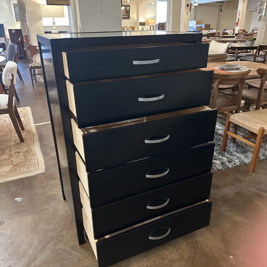 Black dresser with multiple drawers in a room setting