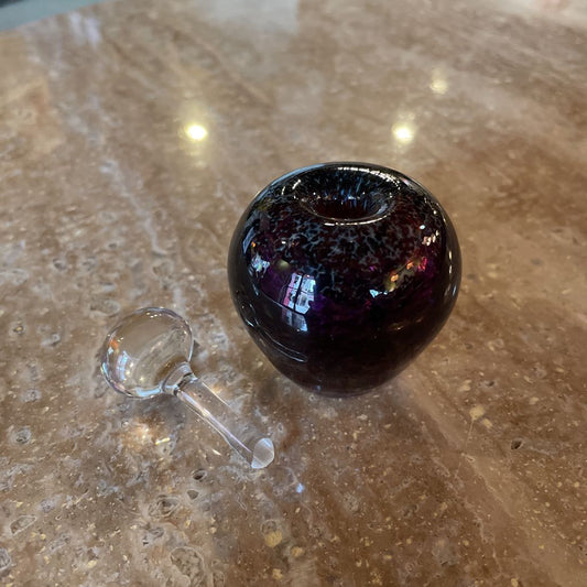 Amethyst-colored glass pipe with clear handle on a textured surface