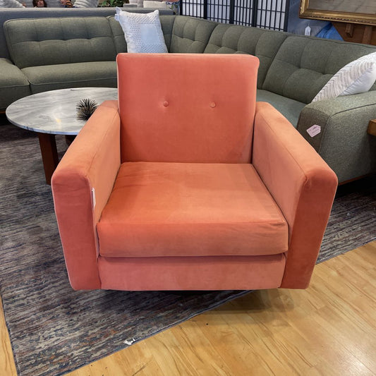 Orange armchair in a room with a gray sectional sofa and wooden floor.