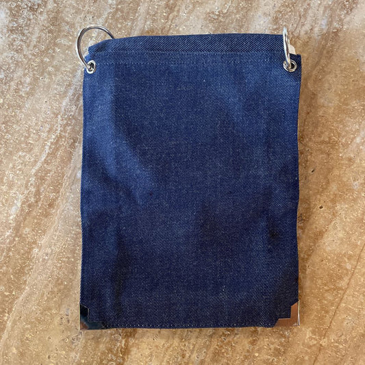 Blue denim bag with metal clips on a beige marble surface