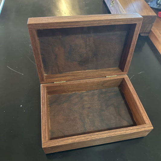 Wooden jewelry box with glass lid on a dark surface