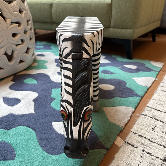 Zebra-themed stool on a colorful rug with a green sofa in the background