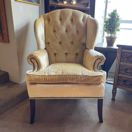 Beige armchair in a room with a plant and furniture.