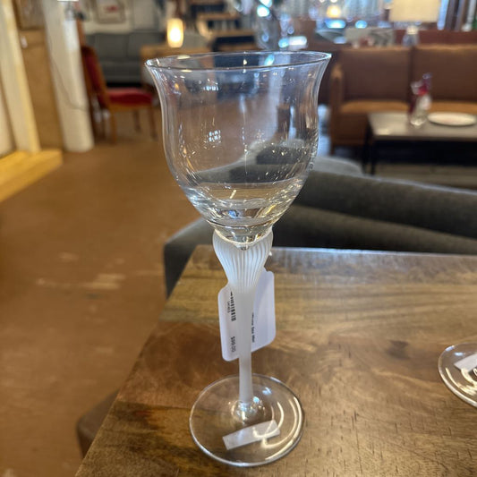Three clear wine glasses on a wooden table with a blurred indoor background
