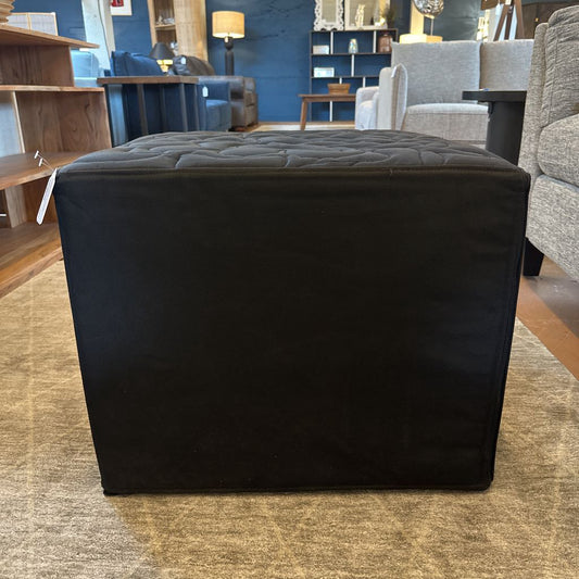 Black upholstered cube ottoman in a furniture store setting