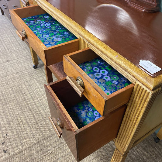 Wooden desk with open drawers revealing floral-patterned fabric interiors.
