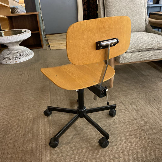 Wooden office chair with black base on a carpeted floor.