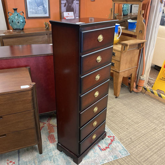Tall wooden dresser with gold knobs in a room with furniture and decor.