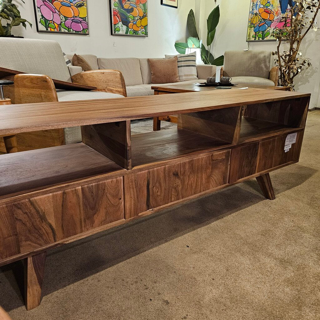 Wooden entertainment console in a living room setting with a sofa and decorative items.