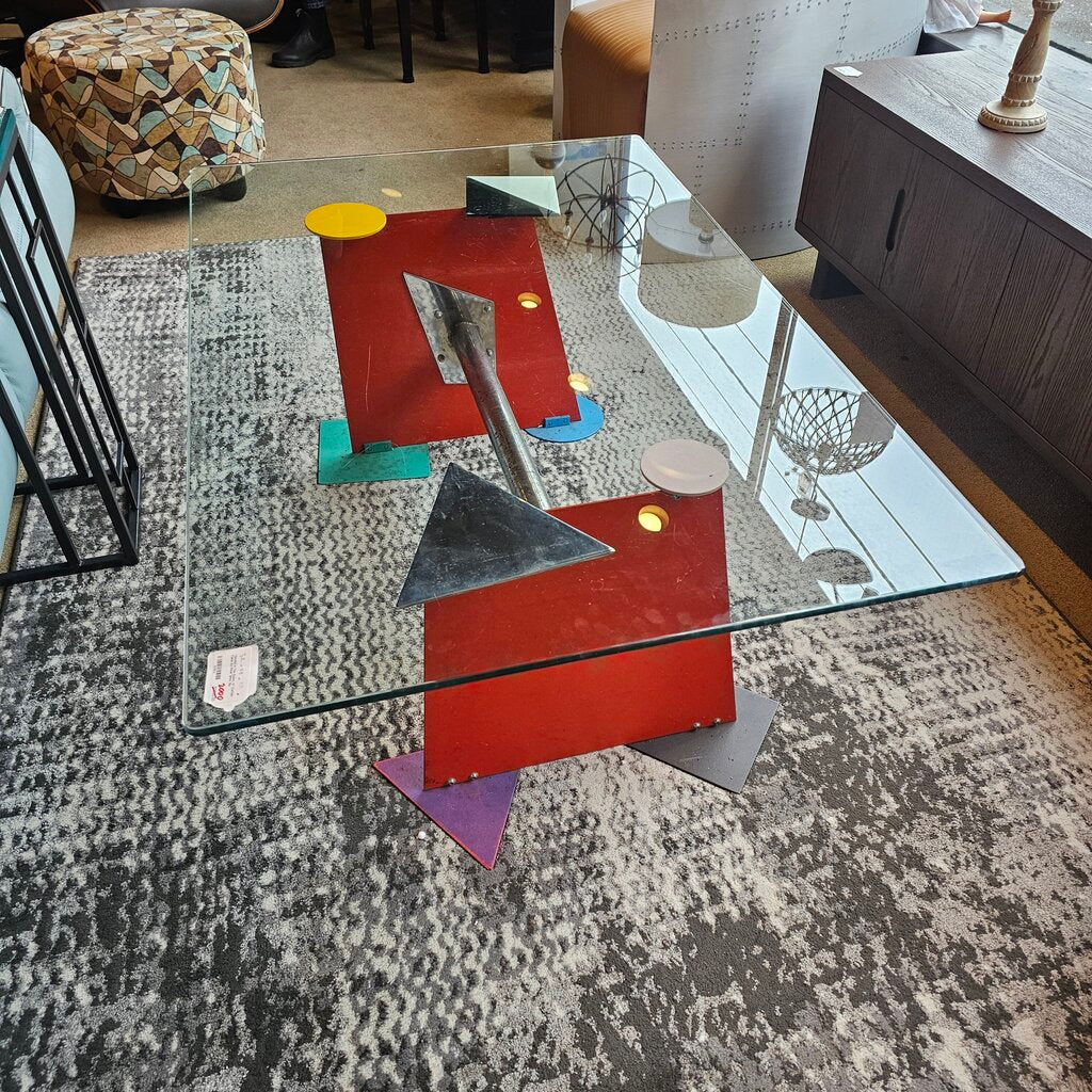 Modern abstract sculpture on a glass table with a patterned rug underneath