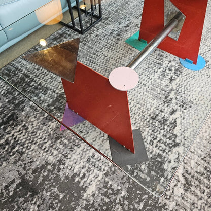 Glass coffee table with metal legs on a textured gray floor