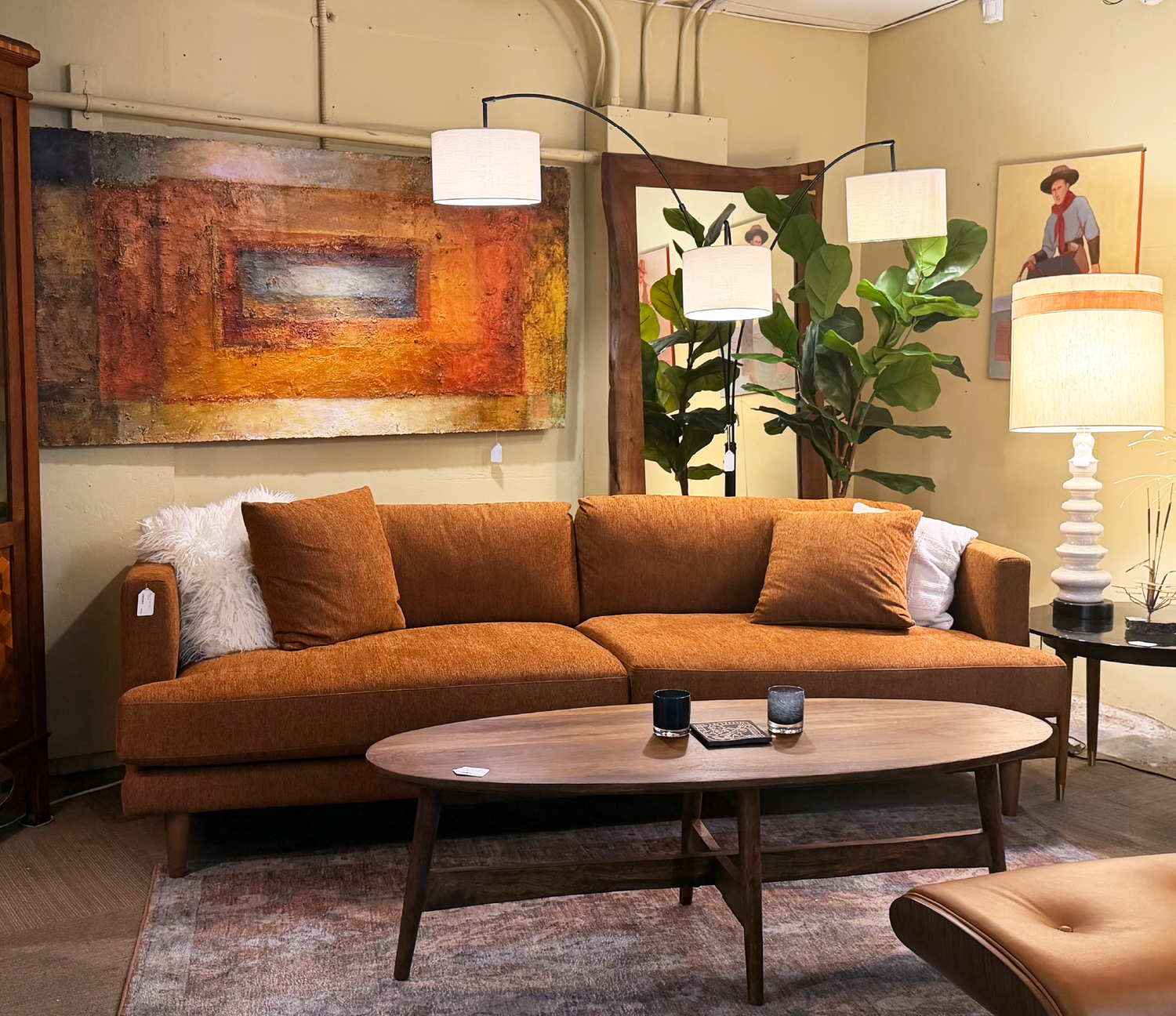 Brown sofa in a living room with a coffee table, lamp, and artwork on the wall.