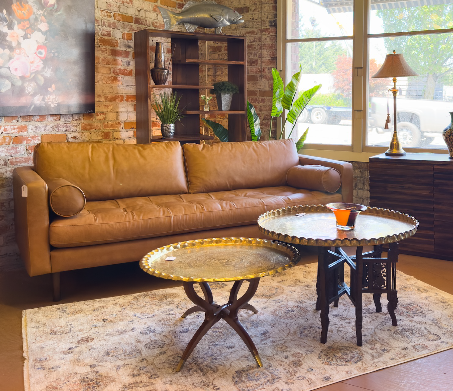 Brown leather sofa in a living room with decorative tables and plants.