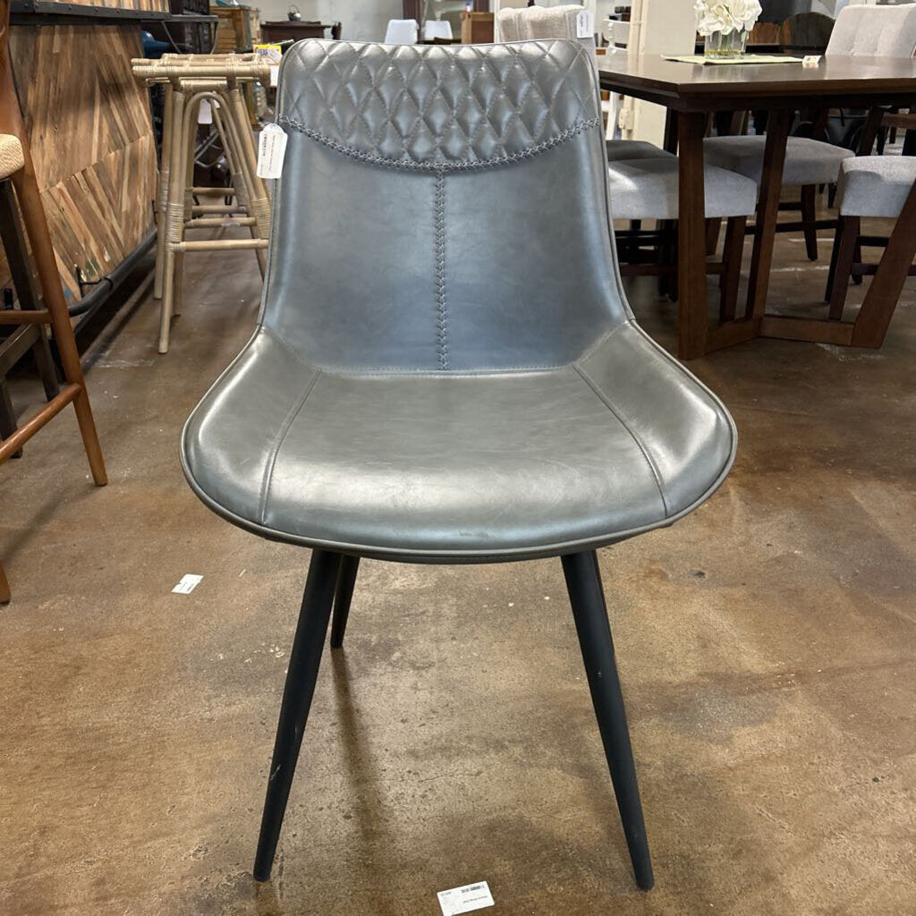 Gray chair with black legs on a brown floor in a furniture store