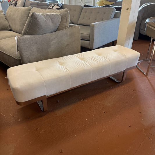 White tufted bench in a room with gray sofas