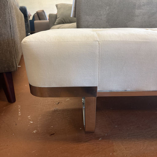 Close-up of a beige sofa with a wooden base on a wooden floor.
