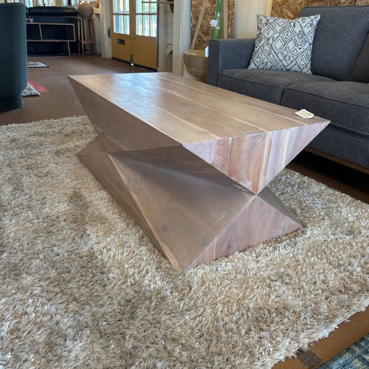 Wooden coffee table in a living room setting with a gray sofa and rug.