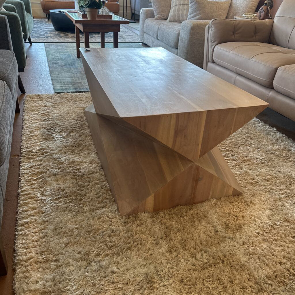 Wooden coffee table in a living room setting with beige sofas and rug.