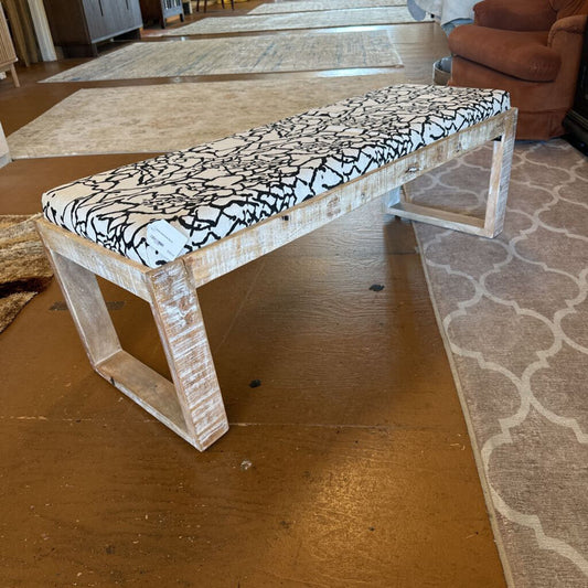 Wooden bench with a patterned cushion on a wooden floor.