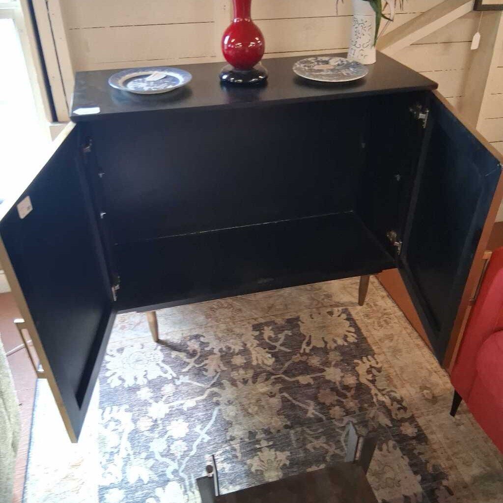 Black cabinet with open doors on a patterned rug