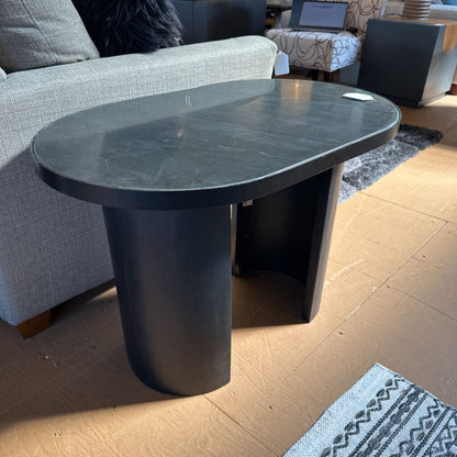 Black marble coffee table in a living room setting with a couch and rug.