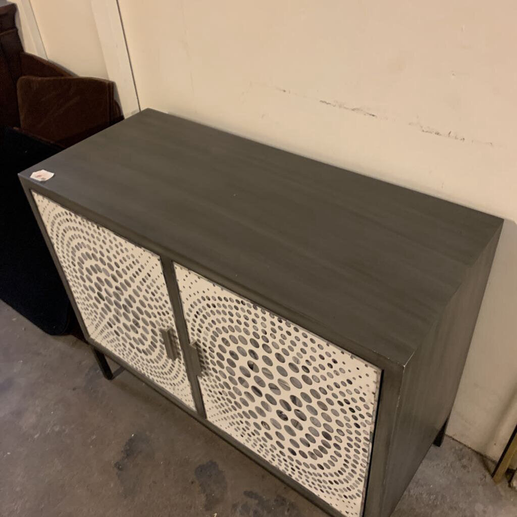 Dark gray cabinet with decorative front panel against a plain wall.