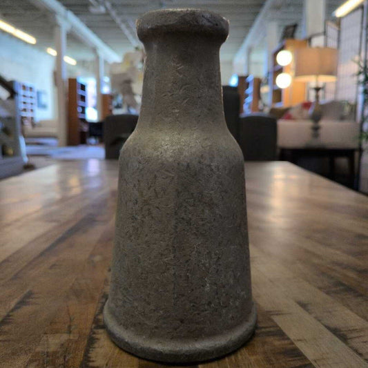Decorative stone vase on a wooden table in a room with furniture and decor.